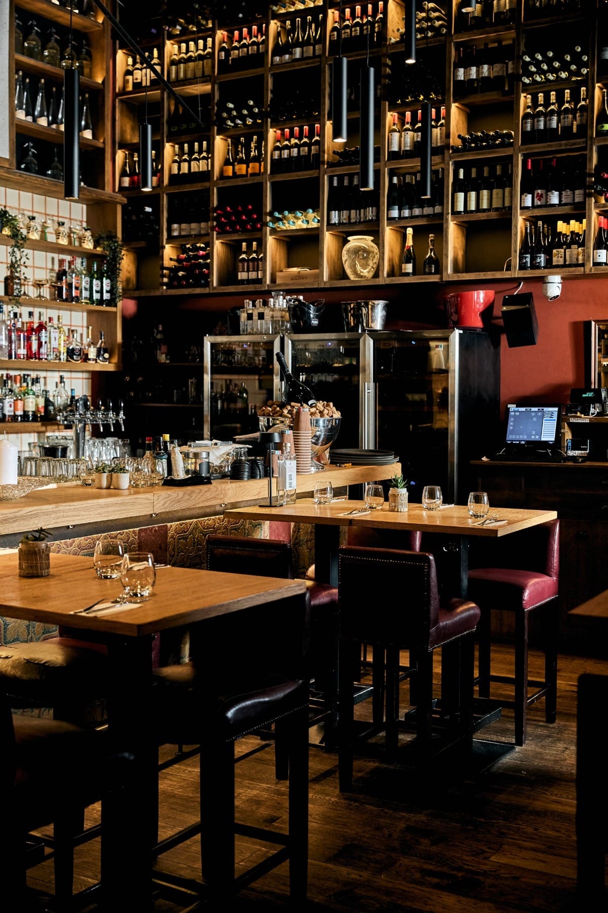 Kismező’s cosy dining room with wooden tables, burgundy chairs and wine shelves